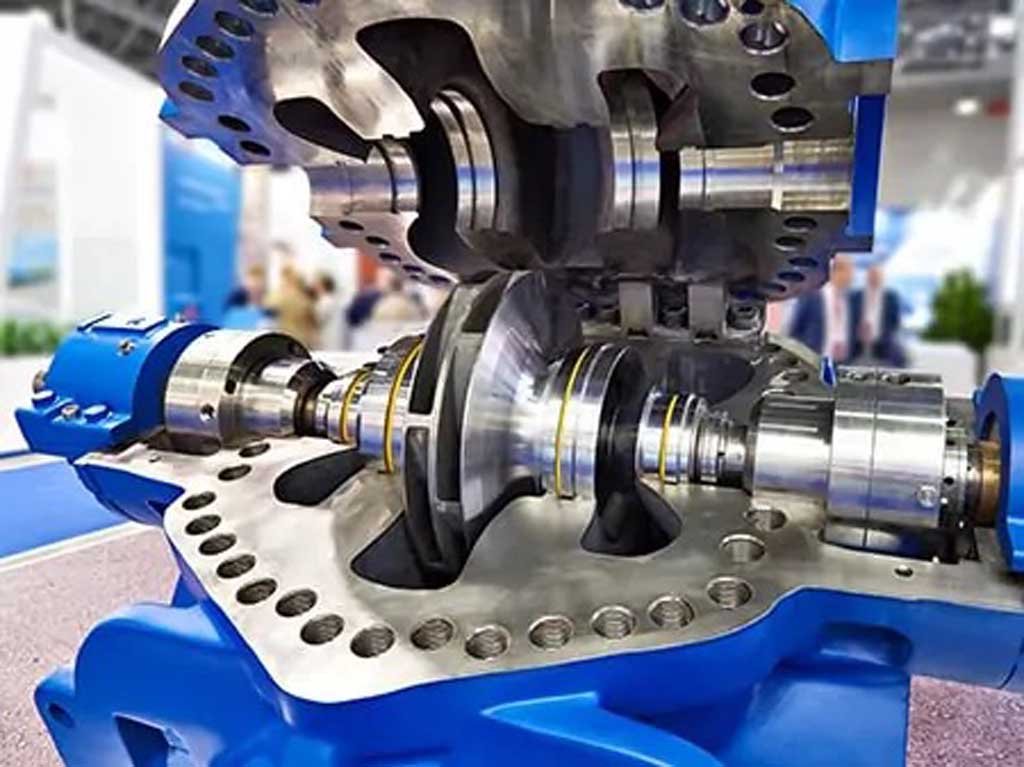 Close-up of a metallic mechanical component assembly with blue casing, possibly a turbine or engine part, displayed indoors.